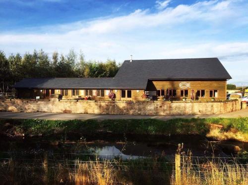 a house with a stone wall next to a body of water at Weston glamping pod in Oswestry