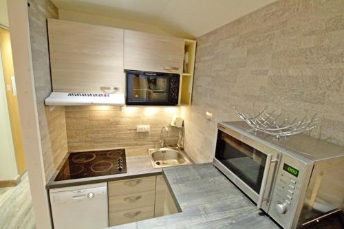une petite cuisine avec un évier et un micro-ondes dans l'établissement Le Hameau De Borsat - Situation privilègiée appartement proche piste MAE-1244, à Tignes