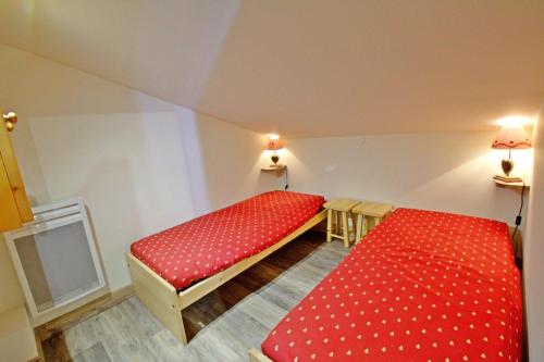 Cette chambre comprend 2 lits avec des draps rouges. dans l'établissement Le Hameau De Borsat - Situation privilègiée appartement proche piste MAE-1244, à Tignes