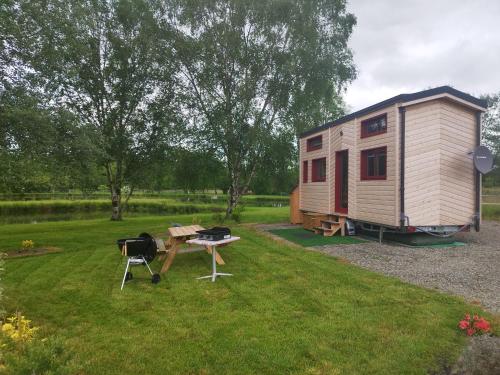 une petite maison et un barbecue dans une cour dans l'établissement Tiny House des Etangs, à Saint-Georges-de-Livoye