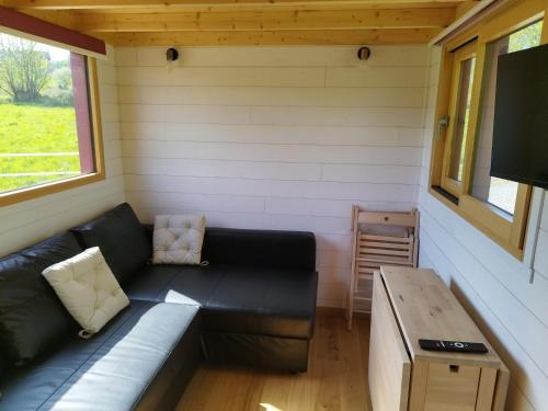 un petit salon avec un canapé et une table dans l'établissement Tiny House des Etangs, à Saint-Georges-de-Livoye