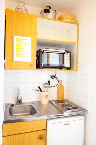 une cuisine avec un évier et un micro-ondes dans l'établissement Rond Point Des Pistes - studio fonctionnel au pied des pistes MAE-1434, à Tignes