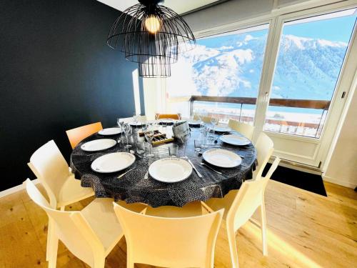 une salle à manger avec une table et des chaises et une grande fenêtre dans l'établissement Résidence Bec Rouge - Appartement rénové ·Skis aux pieds·Balcon MAE-2364, à Tignes