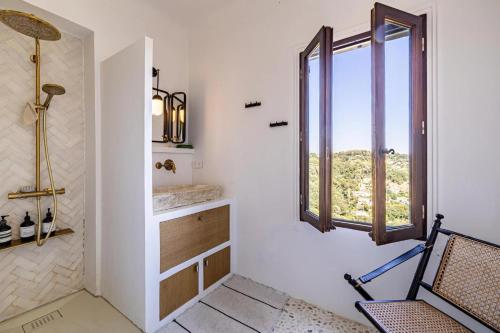 La salle de bains est pourvue d'une chaise et d'une fenêtre. dans l'établissement Appartement de charme à St Paul de Vence, à Saint-Paul-de-Vence