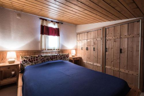 - une chambre avec un lit bleu et des placards en bois dans l'établissement Résidence Rosuel - Appartement avec une vue dégagée sur le lac MAE-2544, à Tignes