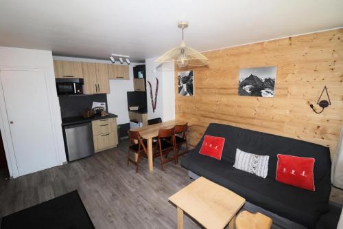 un salon avec un canapé noir et une cuisine dans l'établissement Résidence Grande Balme Ii - Appartement rénové et lumineux MAE-2604, à Tignes