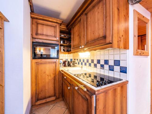 Elle comprend une petite cuisine avec des placards en bois et un évier. dans l'établissement Résidence Ecrin Des Neiges - Beau 2 pièces cabine au coeur de Val Claret MAE-2634, à Tignes