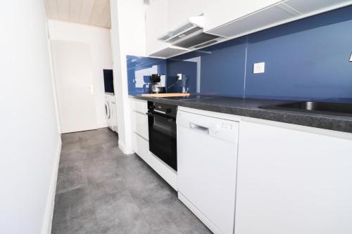 La cuisine est équipée de placards blancs et d'un four avec plaques de cuisson noires. dans l'établissement Résidence Bec Rouge - Appartement lumineux·Skis aux pieds·Balcon MAE-2744, à Tignes