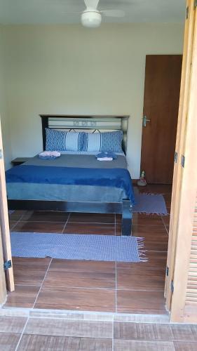 a bedroom with a bed with blue sheets and wooden floors at Casa em São Francisco Xavier sp in São Francisco Xavier
