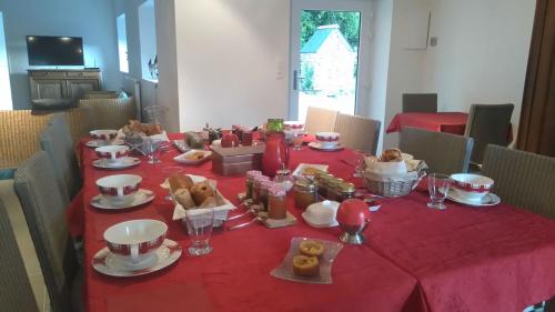 einen Tisch mit einem roten Tischtuch mit Futter drauf in der Unterkunft Domaine du Grand Condest Chambres d'Hôtes in Nivillac