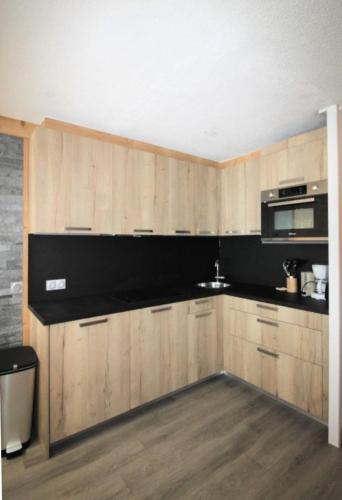 - une cuisine avec des placards en bois et un four micro-ondes dans l'établissement Le Pramecou - Dans une residence calme a proximité des pistes MAE-5024, à Tignes