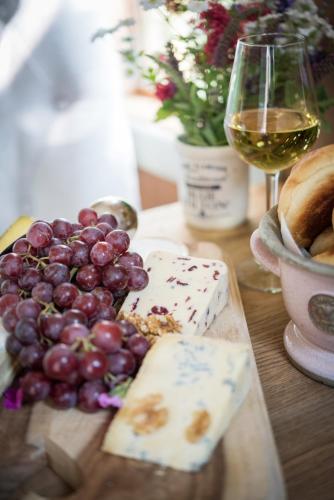 a table with cheese and grapes and a glass of wine at The Treehouse at Salcombe Farm in Salcombe