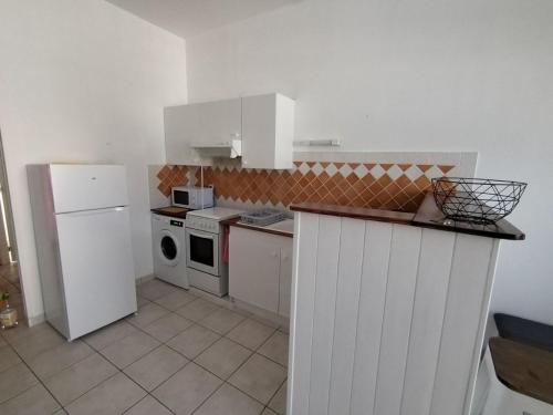 Il comprend une cuisine équipée d'un réfrigérateur blanc et d'une cuisinière. dans l'établissement T2 proche chatelaillon plage, à Salles-sur-Mer