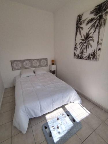 - une chambre avec un lit blanc et des palmiers dans l'établissement T2 proche chatelaillon plage, à Salles-sur-Mer