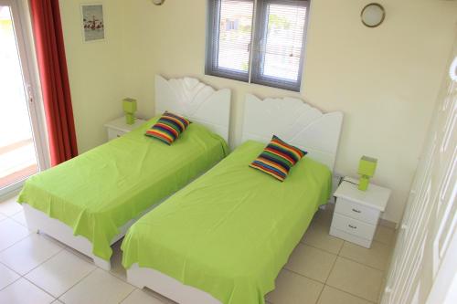 2 letti in una camera con lenzuola verdi di CAS IGUANA - Curacao - Villapark Fontein - Ferienhaus mit Pool a Fontein