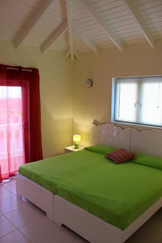 a bedroom with a large bed with a green blanket at CAS IGUANA - Curacao - Villapark Fontein - Ferienhaus mit Pool in Fontein