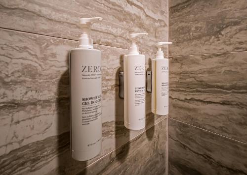three white shampoo bottles on a wall in a bathroom at Spark by Hilton Montgomery EastChase in Montgomery