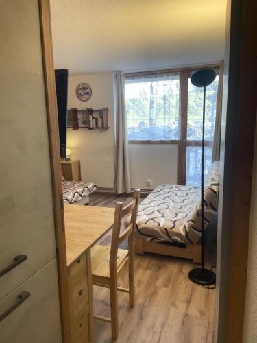 Cette chambre comprend une table, un lit et une fenêtre. dans l'établissement Résidence Hameaux Ii - Studio rénové 3 personnes - Plagne Village MAE-7324, à Aime La Plagne
