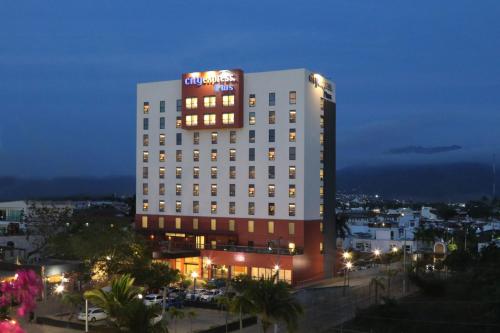a tall white building with a sign on top of it at City Express Plus by Marriott Puerto Vallarta in Puerto Vallarta