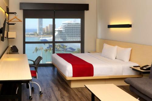 a hotel room with a bed and a large window at City Express Plus by Marriott Puerto Vallarta in Puerto Vallarta