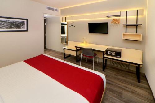 a room with a bed and a desk and a table at City Express Plus by Marriott Puerto Vallarta in Puerto Vallarta