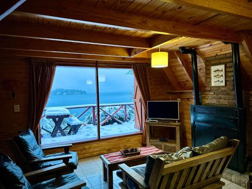 a living room with a large window in a cabin at Cabañas Aucaman in Villa Pehuenia