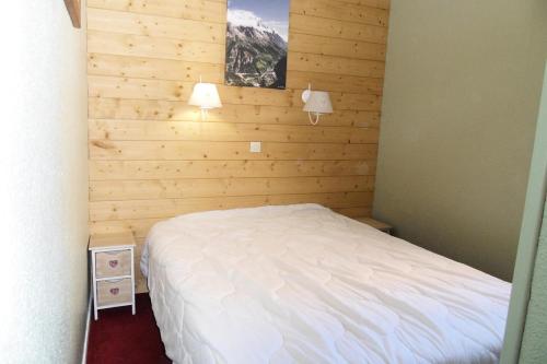 une chambre avec un lit blanc et un mur en bois dans l'établissement Résidence Themis - 3 Pièces pour 7 Personnes 284, à Aime La Plagne