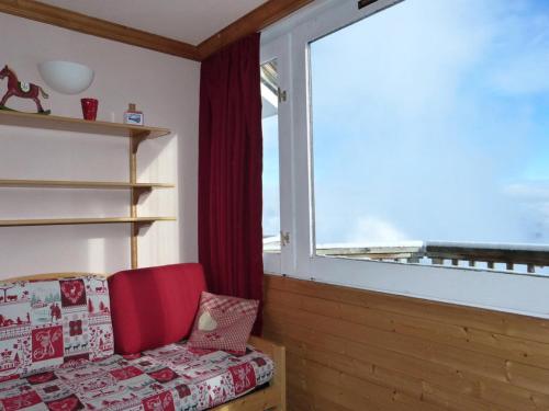 un fauteuil rouge dans une chambre avec une grande fenêtre dans l'établissement Résidence Diamant - Studio pour 4 Personnes 114, à Aime La Plagne