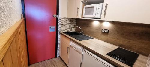 une petite cuisine avec un évier et un micro-ondes dans l'établissement Résidence Chamois - Studio pour 4 Personnes 084, à Aime La Plagne