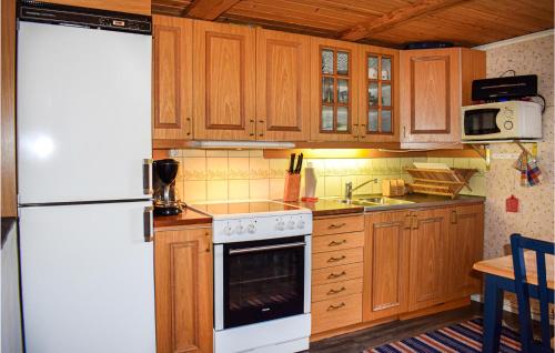 a kitchen with wooden cabinets and a white refrigerator at Two-Bedroom Holiday Home In Rorvik in Rörvik
