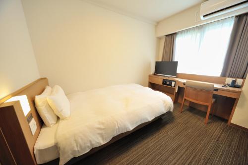 a hotel room with a bed and a desk at Dormy Inn Express Meguro Aobadai Hot Spring in Tokyo