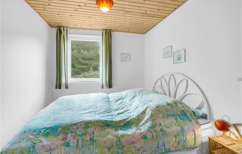 a bedroom with a bed with a comforter and a window at 3 Bedroom Nice Home In Rømø in Tagholm