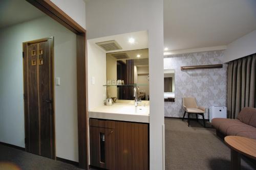 a bathroom with a sink and a living room at Dormy Inn Express Meguro Aobadai Hot Spring in Tokyo
