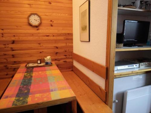 une chambre avec une table et une horloge sur un mur dans l'établissement Résidence Les Glaciers 3 - 2 Pièces pour 5 Personnes 214, à Aime La Plagne