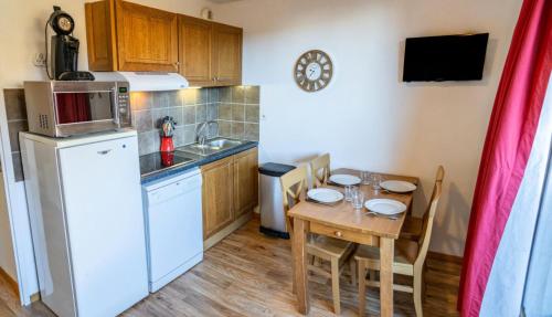 une petite cuisine avec une table et un réfrigérateur dans l'établissement Les Chalets De Bois MÉan - A - Escapade douillette avec vue sur la vallée MAE-7394, aux Orres