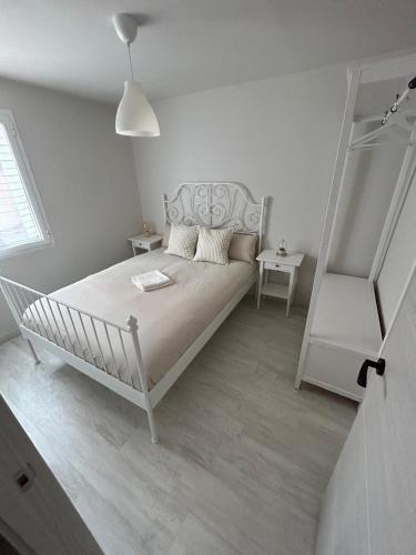a white bedroom with a white bed and a window at Apartamento calera in Burgos