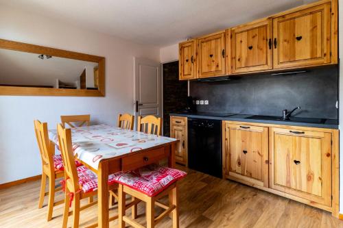 une cuisine avec des armoires en bois et une table avec des chaises dans l'établissement Les Chalets De Bois MÉan - C - Magnifique appartement montagnard aux Orres 1800 MAE-6531, aux Orres