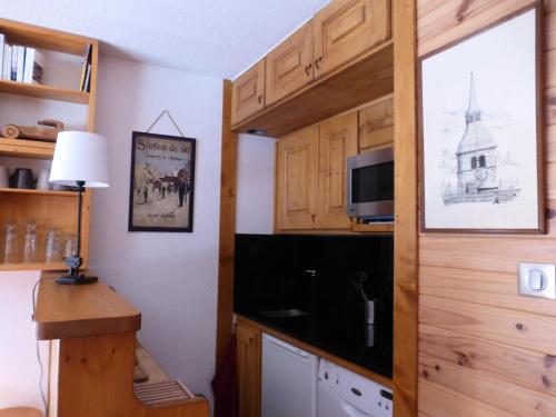 une cuisine avec des placards en bois et une porte avec une télévision dans l'établissement Résidence Les Dauphinelles - Agréable studio à Méribel Altiport proche des pistes MAE-7641, à Les Allues