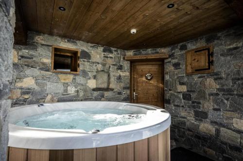 La salle de bains est pourvue d'une grande baignoire et de murs en pierre. dans l'établissement Les Chalets Du Cocoon - 6 Pièces pour 11 Personnes 611, à Aime La Plagne