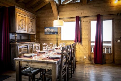 une salle à manger avec une longue table avec des verres à vin dans l'établissement Les Chalets Du Cocoon - CHALET PIERRA MENTA 1 MAE-1641, à Aime La Plagne