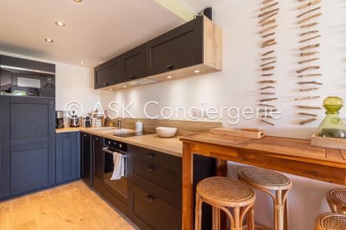 une cuisine avec des placards noirs et des tabourets de bar dans l'établissement Close to Gigaro beach, surrounded by nature, à La Croix-Valmer