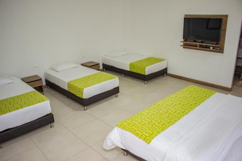 a room with three beds and a flat screen tv at Hosteria Guaracú in San Jerónimo
