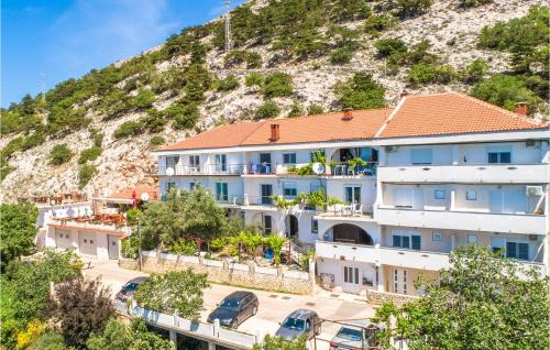 a large white building with a hill in the background at Nice Apartment In Stara Baska 1 in Stara Baška