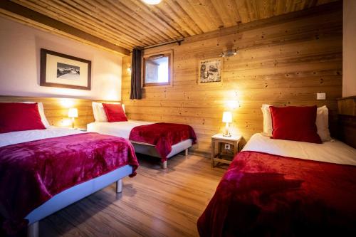 deux lits dans une chambre aux murs en bois dans l'établissement Les Chalets Du Cocoon - CHALET PIERRA MENTA 2 MAE-1621, à Aime La Plagne