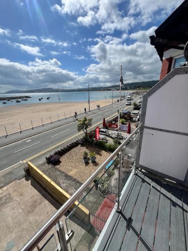 a view of a beach from a balcony with a bench at Stunning Sea View Apartment With Balcony & Parking in Rhos-on-Sea