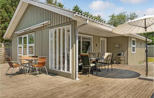 a deck with a table and chairs and an umbrella at Holiday Home Bjergbovej Blåvand Xi in Blåvand