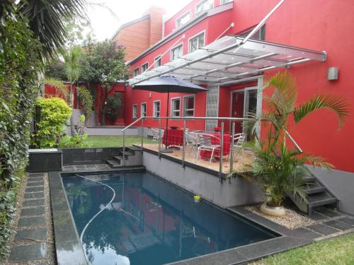 a swimming pool in front of a red building at Red Square Home in Pretoria