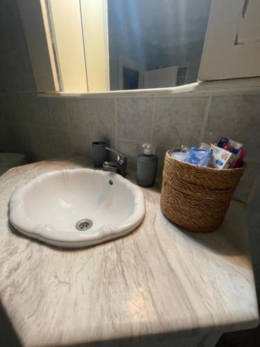 a bathroom sink with a basket of toiletries on a counter at Christina's Apartment in Stratónion