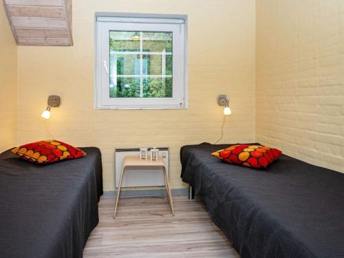 two beds in a room with a table and a window at 12 person holiday home in Ulfborg-By Traum in Ulfborg