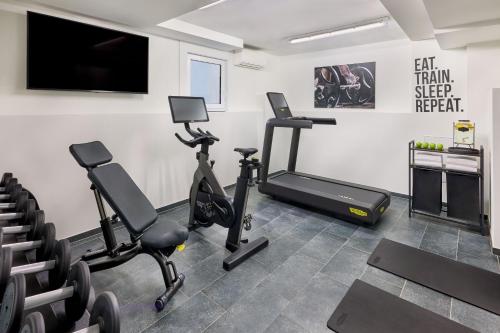 a gym with exercise bikes and a flat screen tv at the Deutz, a Tribute Portfolio Hotel in Cologne